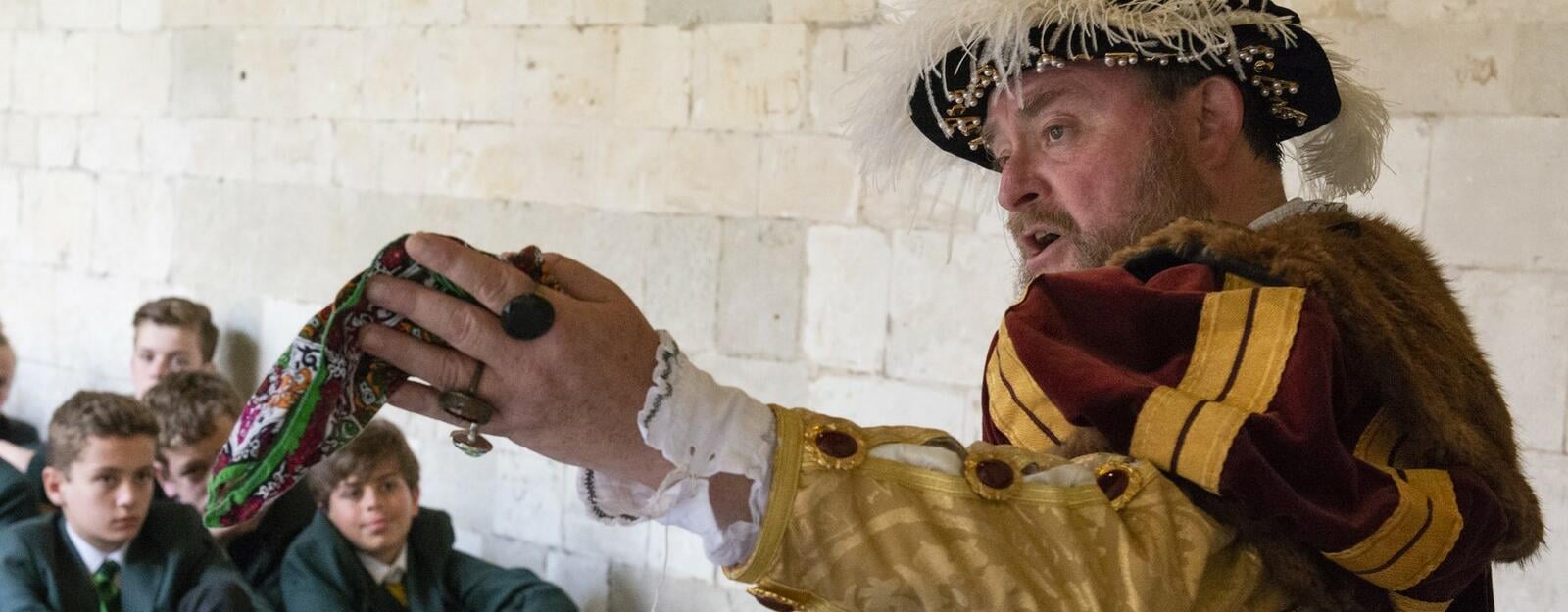 Actor dressed as Henry 8th talks to school pupils