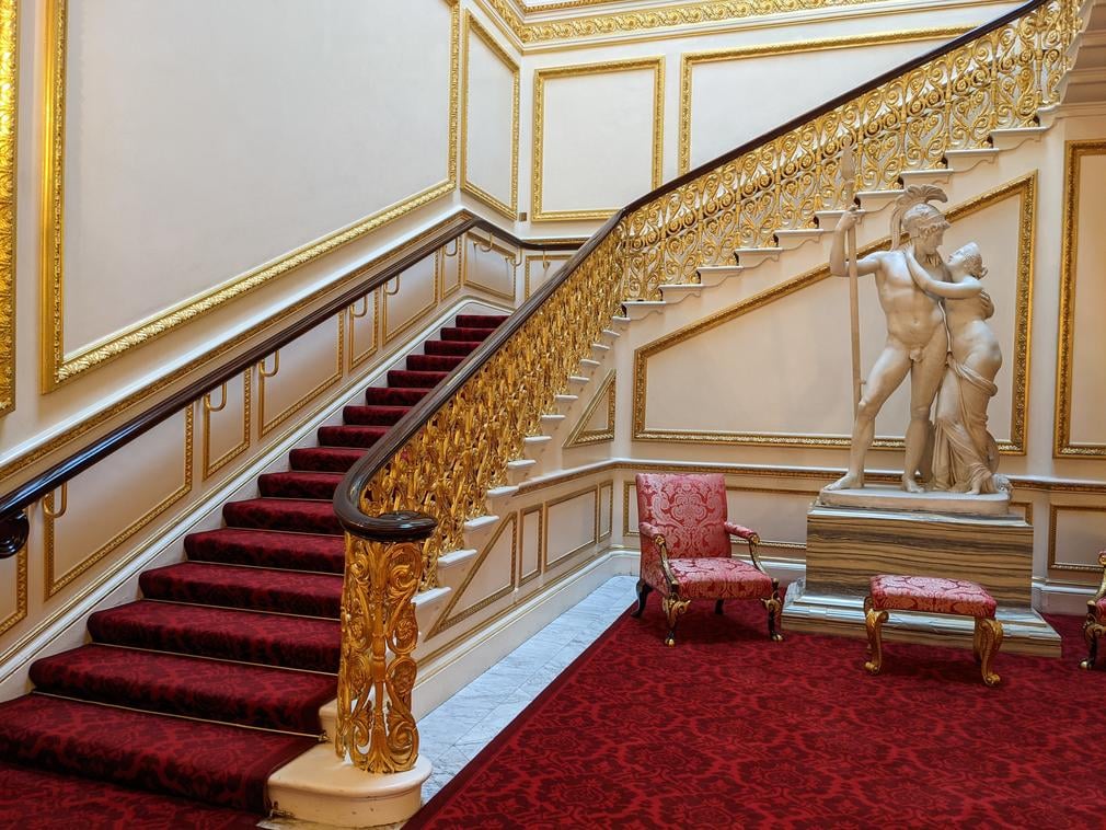 Carpeted staircase with marble statue at the bottom