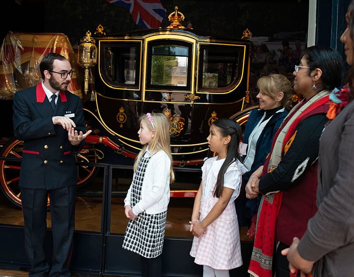 Warden talks to people in front of carriage