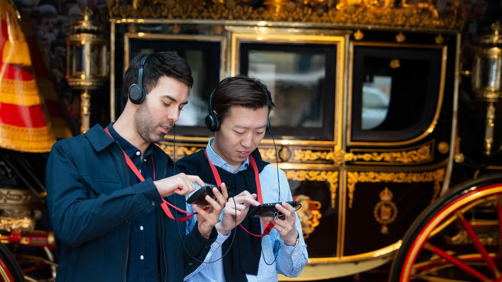 Two people look at multimedia guides in front of carriage